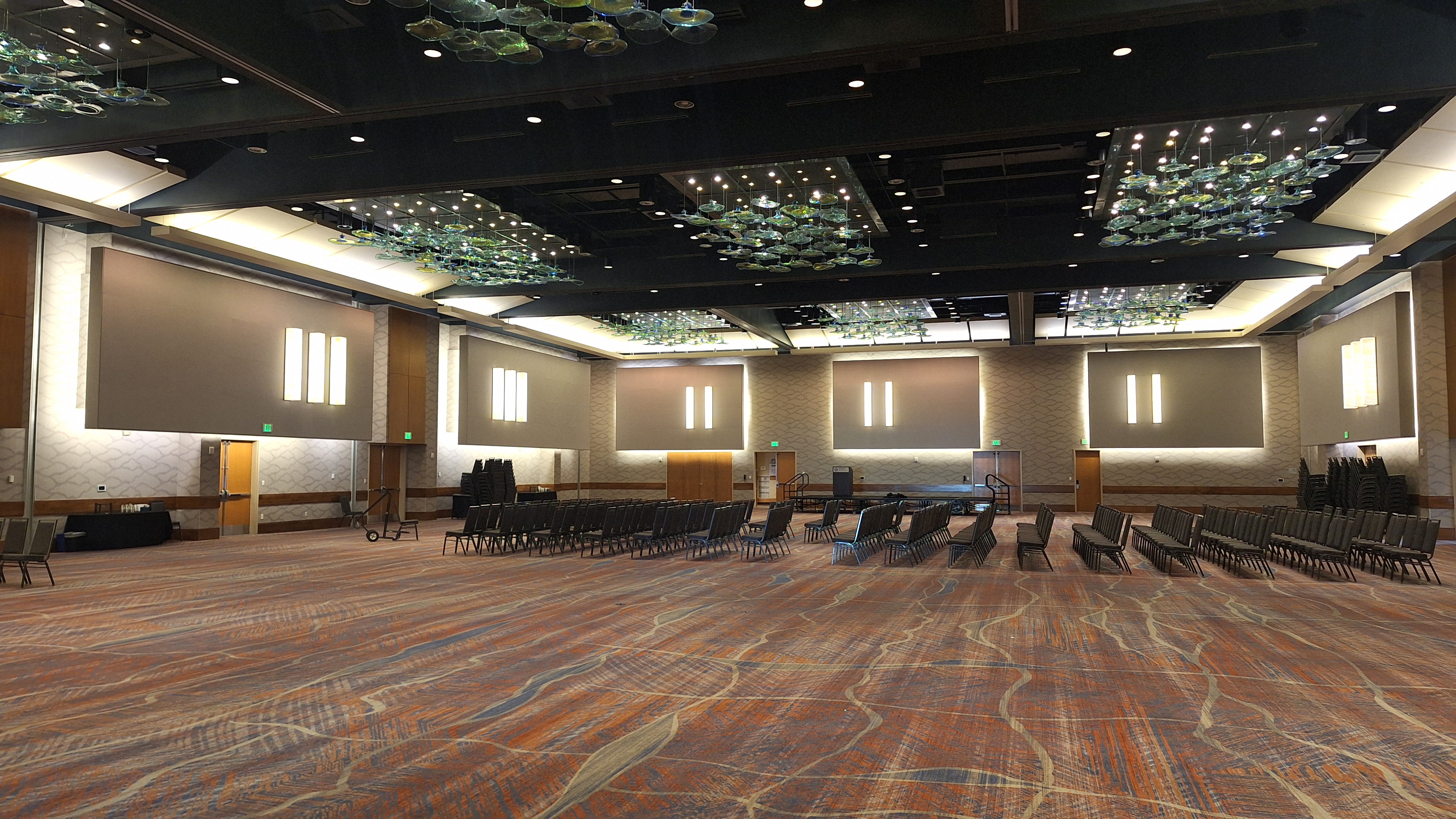 The walls of the smaller conference rooms had been removed, revealing the small rooms to have only been a mere section of one large Ballroom, equipped with rows of perfectly-parallelized chairs, preparing to seat the crowd who no longer wandered the halls